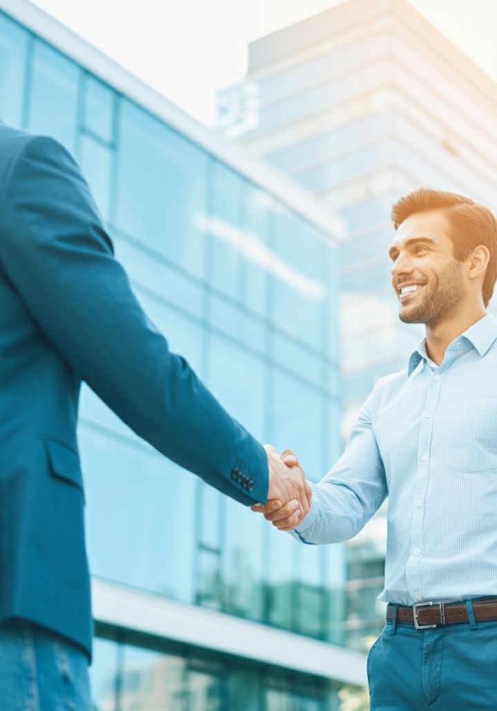 Two business people shaking hands in front of an office building